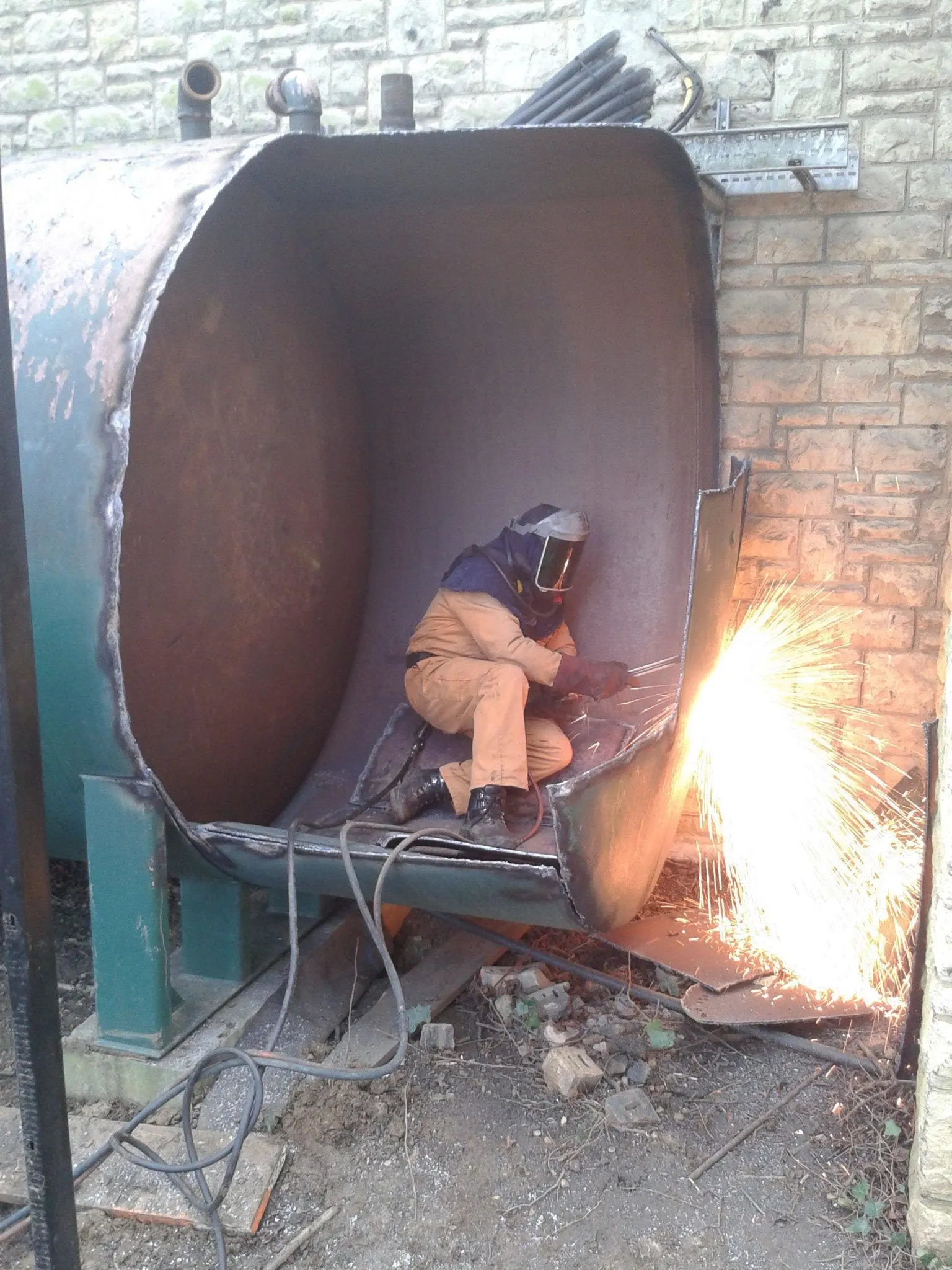 A man if PPE cutting a fuel tank 